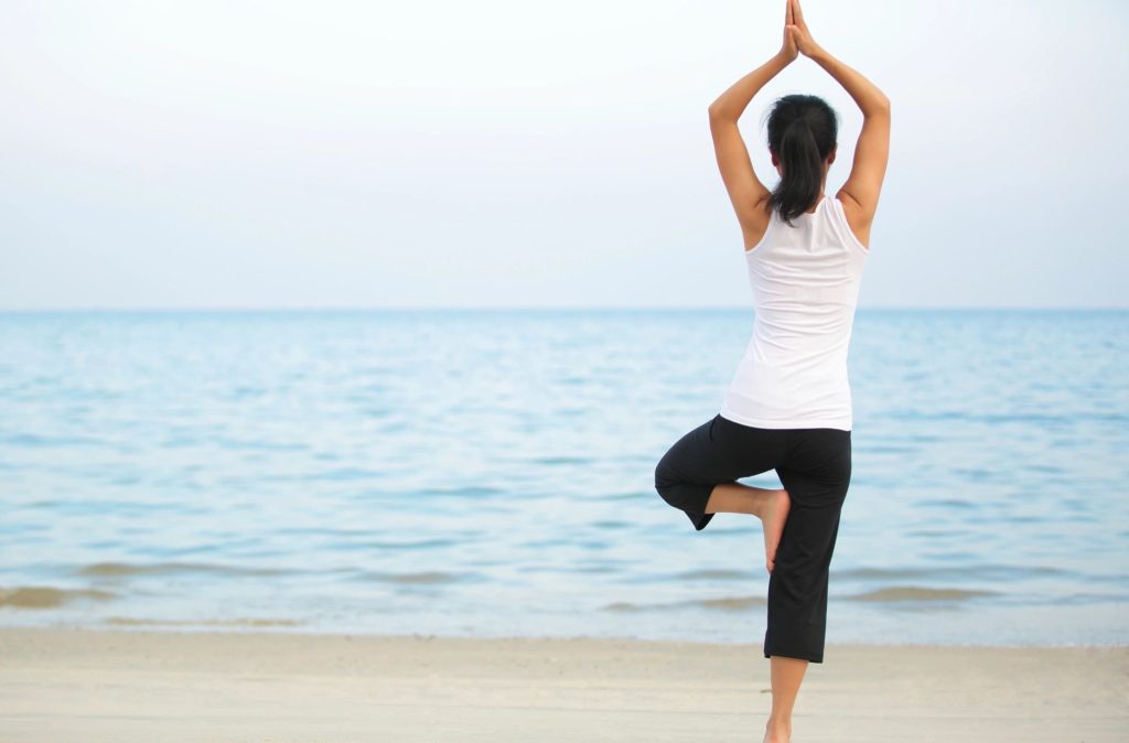 Woman doing yoga on the beach after discovering successful anxiety treatment in Savannah, GA