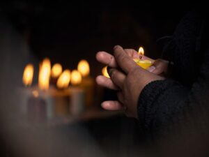 A close up of a person holding a candle in front of a candlelight vigil. Learn tips on coping with grief by contacting a grief counselor in Savannah, GA, or searching for “counselor near me” today. Grief counseling Savannah GA can support you. 
