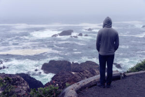 A teen stands alone looking out at a cloudy shore. This could represent the isolation an anxiety therapist in Savannah, GA can help overcome. Learn how counseling for teenagers in Savannah, GA can offer support by searching for an anxiety therapist near me today.
