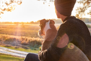 A teen sits with their dog as they watch the sunrise. This could symbolize how counseling for teenagers in Savannah, GA can offer support.
