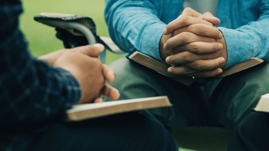 two people's hands on bibles in faith based counseling