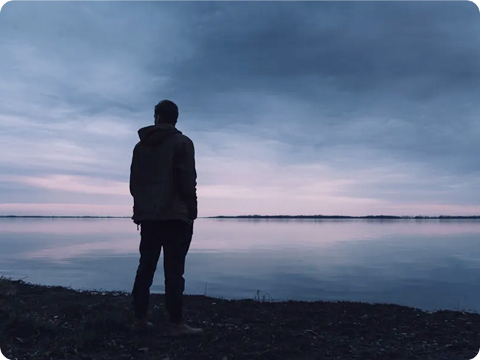 person standing alone by a calm lake